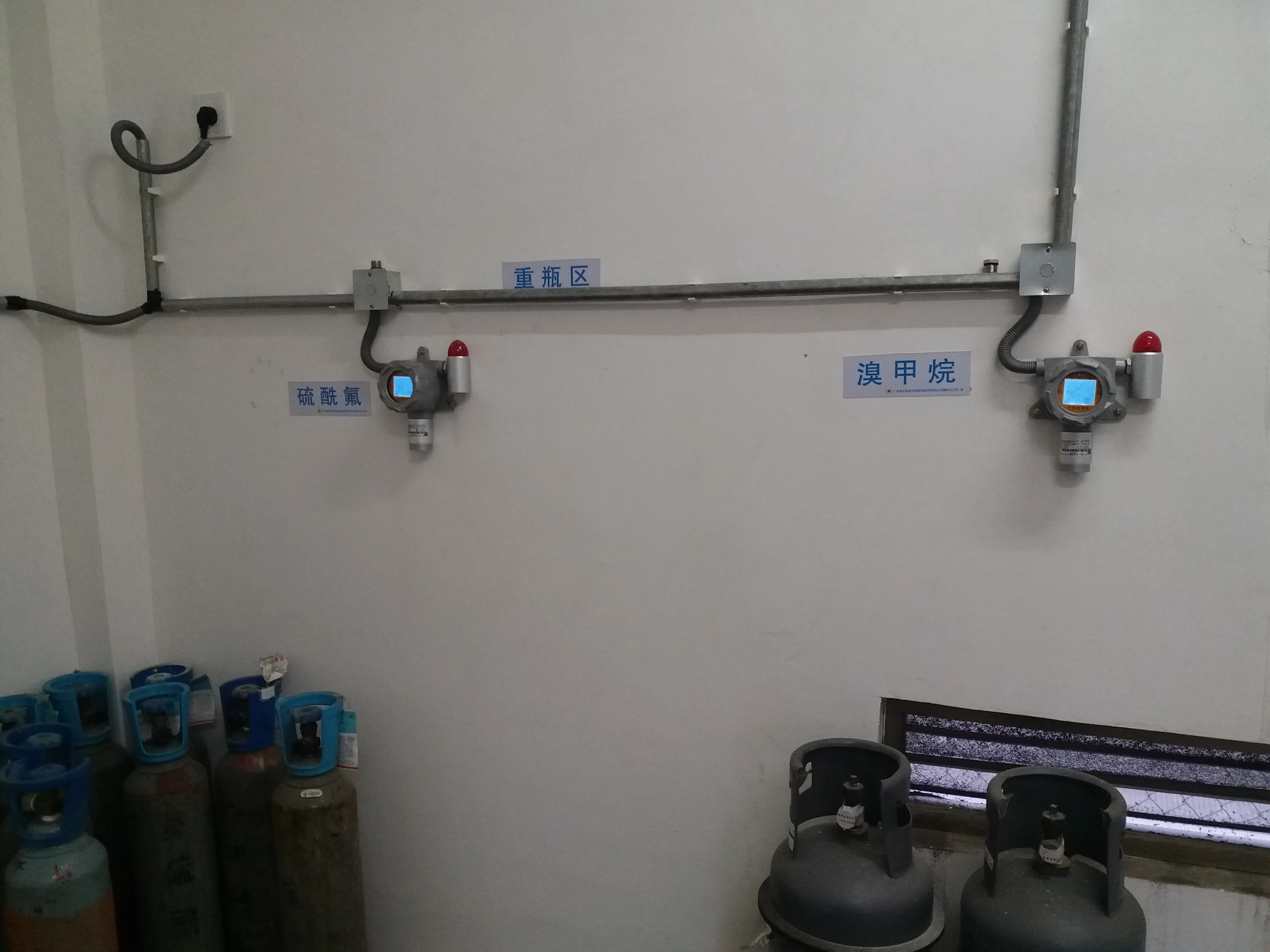 Fixed Gas Detector installed on the wall of an industrial gas cylinder storage room monitoring SO2F2 and CH3Br