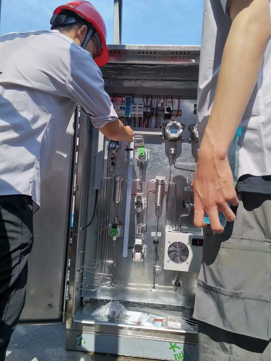 Skyeaglee engineers debugging the heavy-duty online gas analyzer cabinet and internal filtration pipelines at an outdoor industrial site