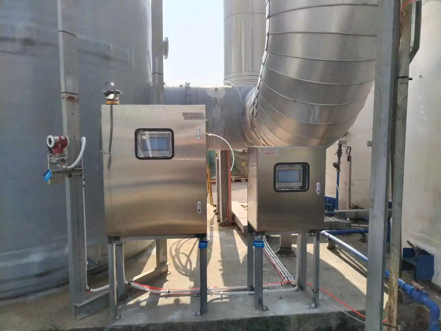 Inlet and outlet odor control gas monitors installed on a blue steel walkway at an outdoor sewage treatment facility