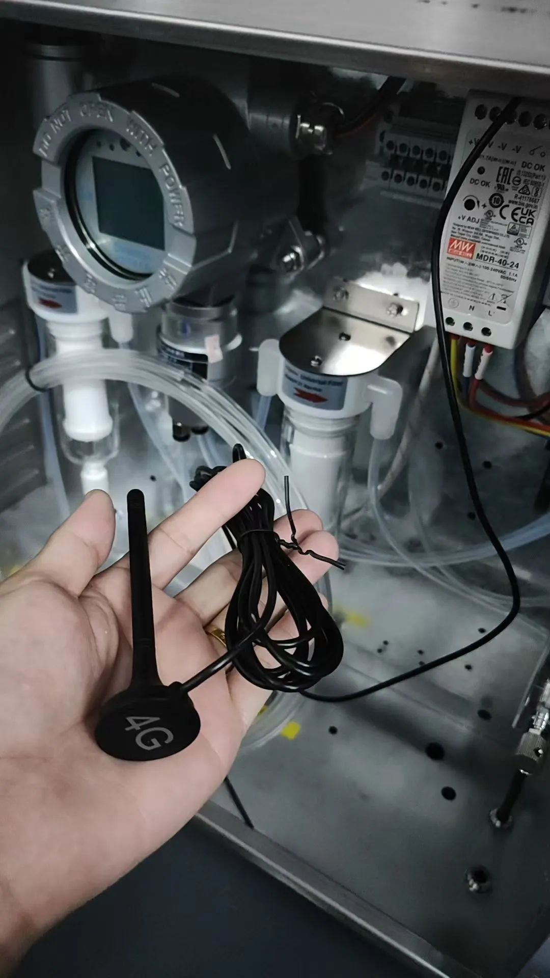 Engineer holding a 4G wireless transmission antenna inside the VOC monitoring cabinet