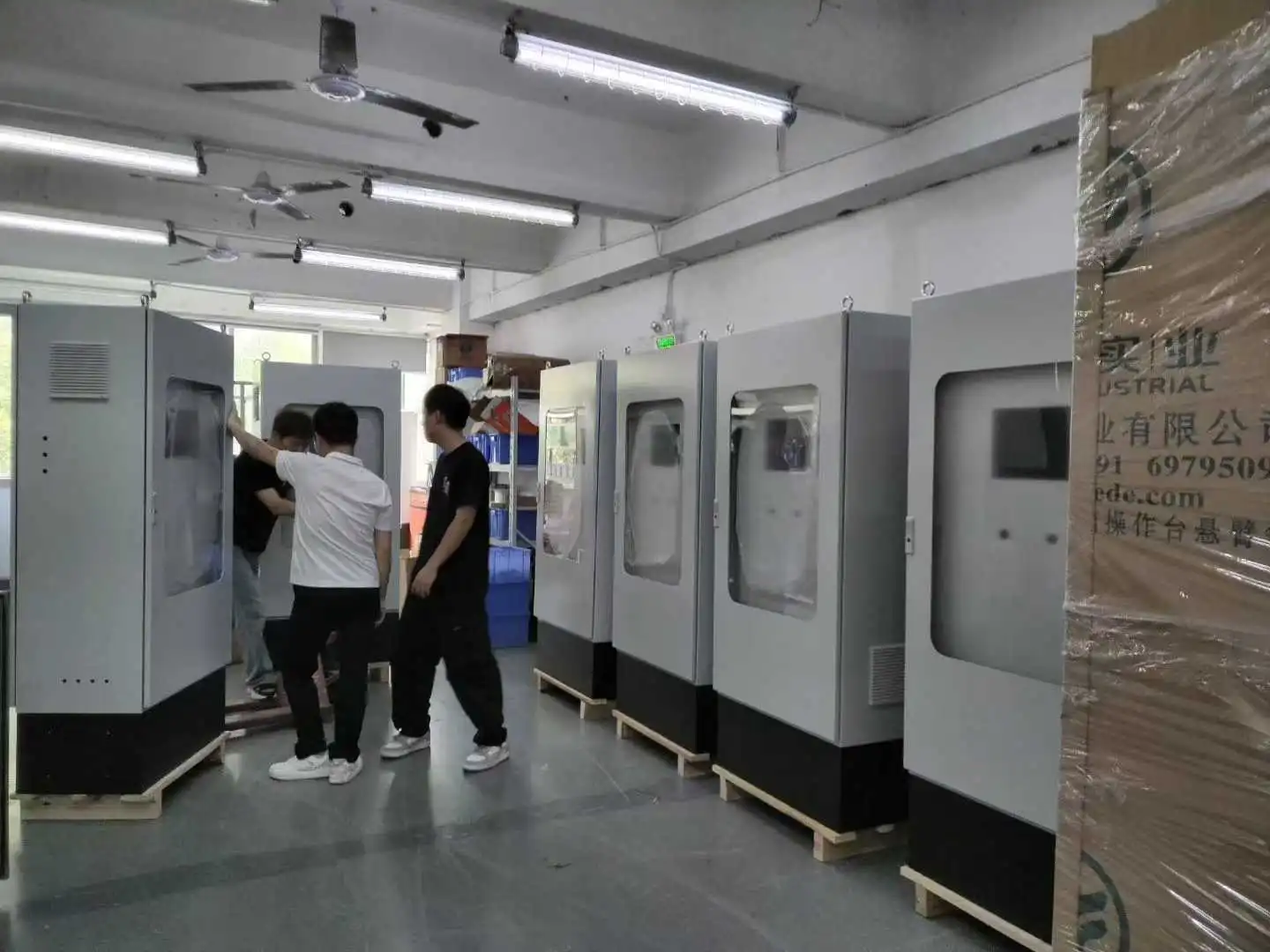 Skyeaglee factory workers assembling large HNAG1000 CEMS System cabinets on the production line