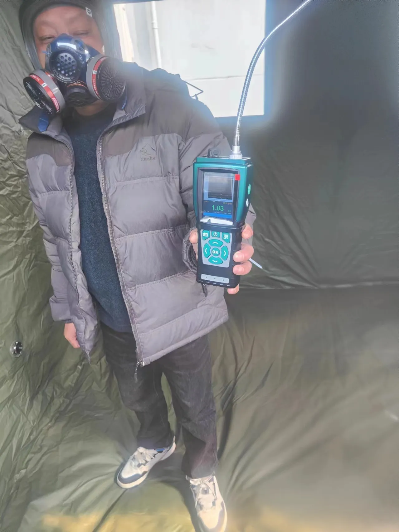 Technician using handheld gas monitor in confined space safety inspection